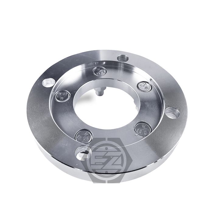The Wheel Adapter 4 Lug 156 To 5 Lug 4.5 (Pair) is a circular billet aluminum flange with a shiny finish, featuring several bolt holes evenly spaced around the edge, designed for ATVs with a larger central opening and an embossed logo on a white background.
