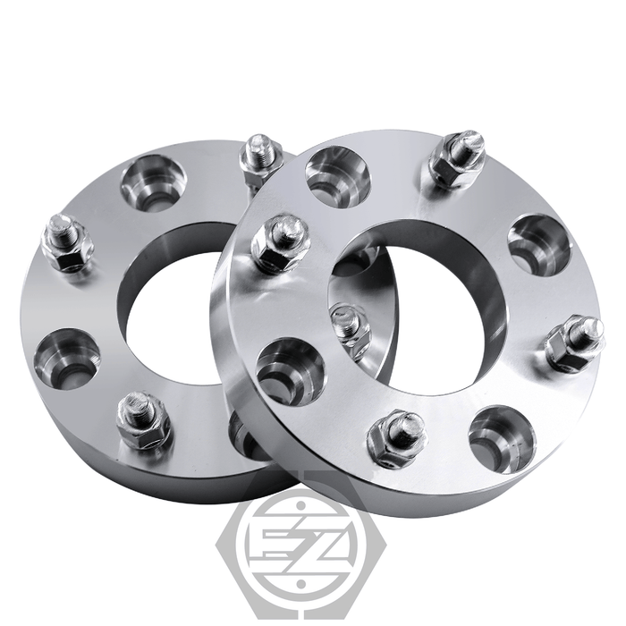 A pair of Mazda Wheel Adapter 4 Lug 110 to 4 Lug 137 is displayed upright with shiny metal spacers, multiple holes, and bolts. A hexagon logo with a geometric design highlights the precision of these adapters.